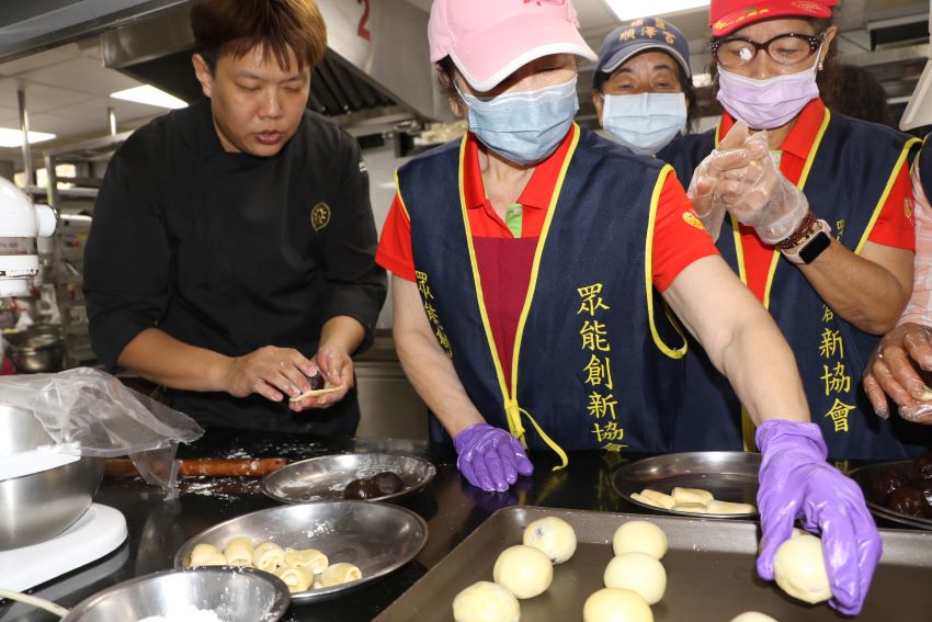 《圖說》黎明技術學院餐飲管理系劉子賓老師（左）指導眾能志工如何包餡。〈社會局提供〉
