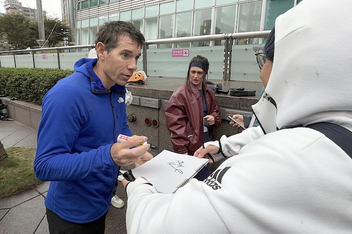 美國自由攀岩好手霍諾德左）將於24日挑戰徒手攀登台北101，他21日幫粉絲簽名。圖/中央社