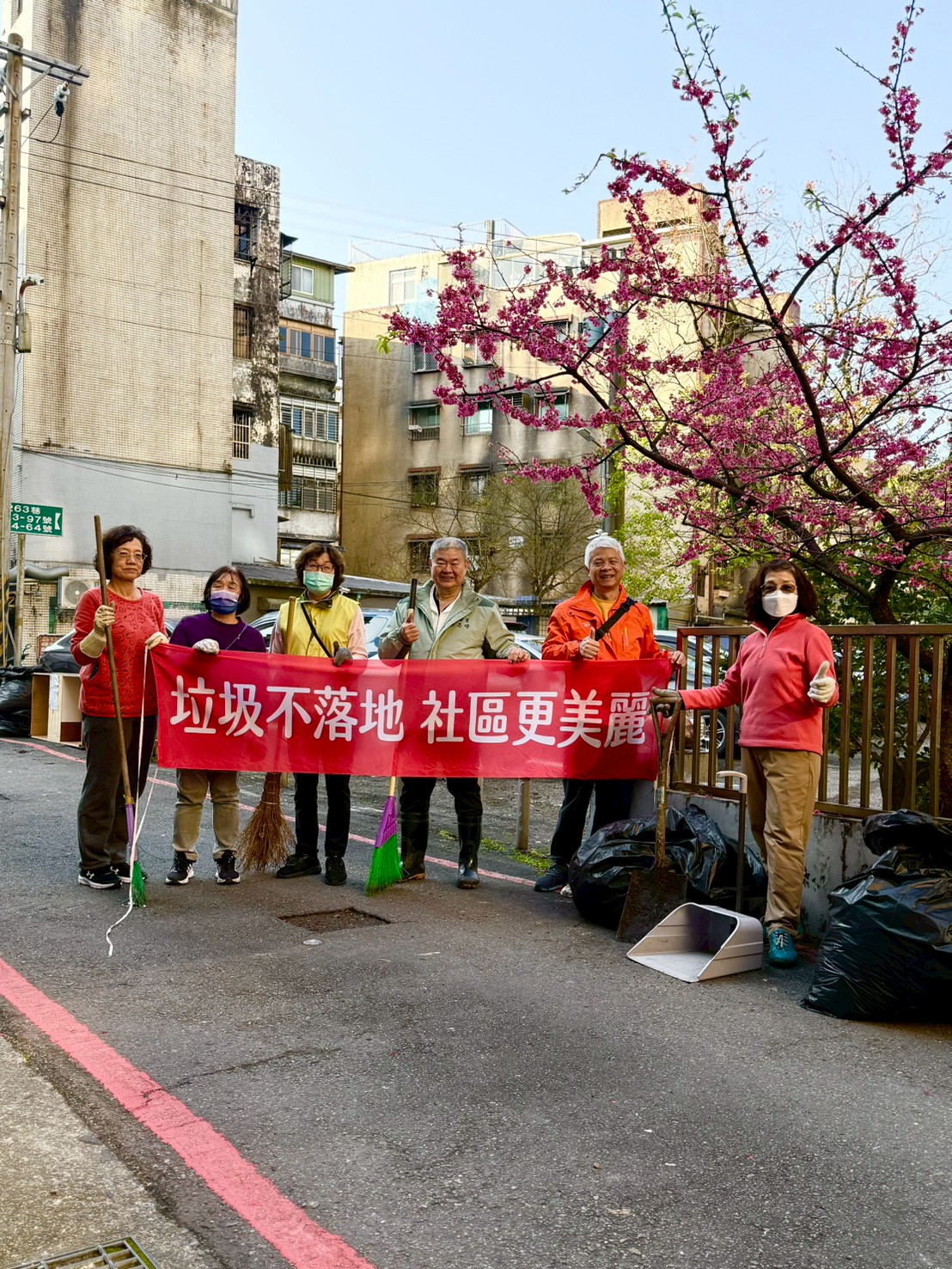 圖為蔡志峰前理事長(右三)率六合志工清掃環境乾淨家園，並於美麗的櫻花下宣導「垃圾不落地、社區更美麗」/六合志工提供