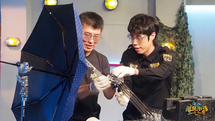  胡子（右）在「鹹魚實驗室」使用親手打造的「揮砍裝置」，測試雨傘在隨機傷人現場是否真的能抵擋美工刀的攻擊。圖/公視提供